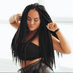 Black woman with long braided hair grooving with her arms up and hip pushed out