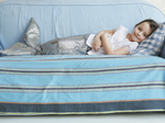 Image of a girl in a mermaid tail costume laying on a blue couch
