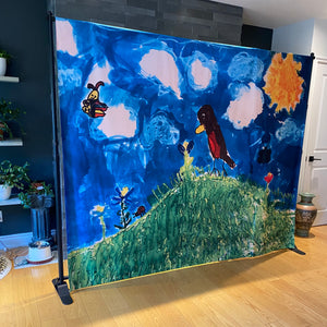 
                  
                    metal stand with backdrop sheet with a children's drawing of a sky and birds on it
                  
                